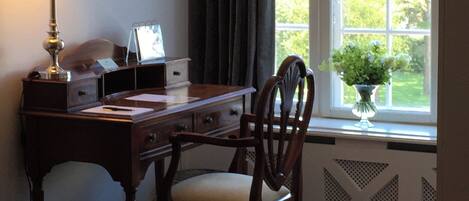 A study room with a desk, chair, lamp, and a window with curtains.