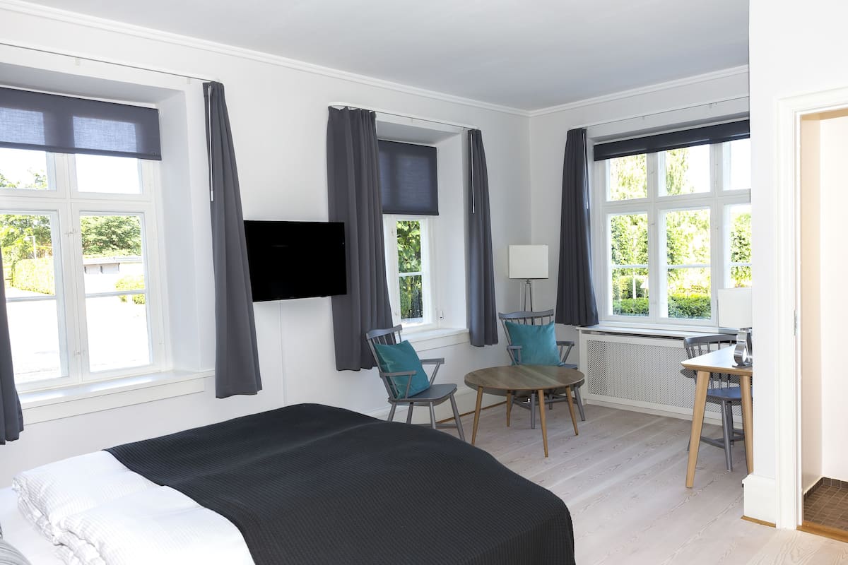 A hotel room with a bed, a desk, a chair, and a TV mounted on the wall.