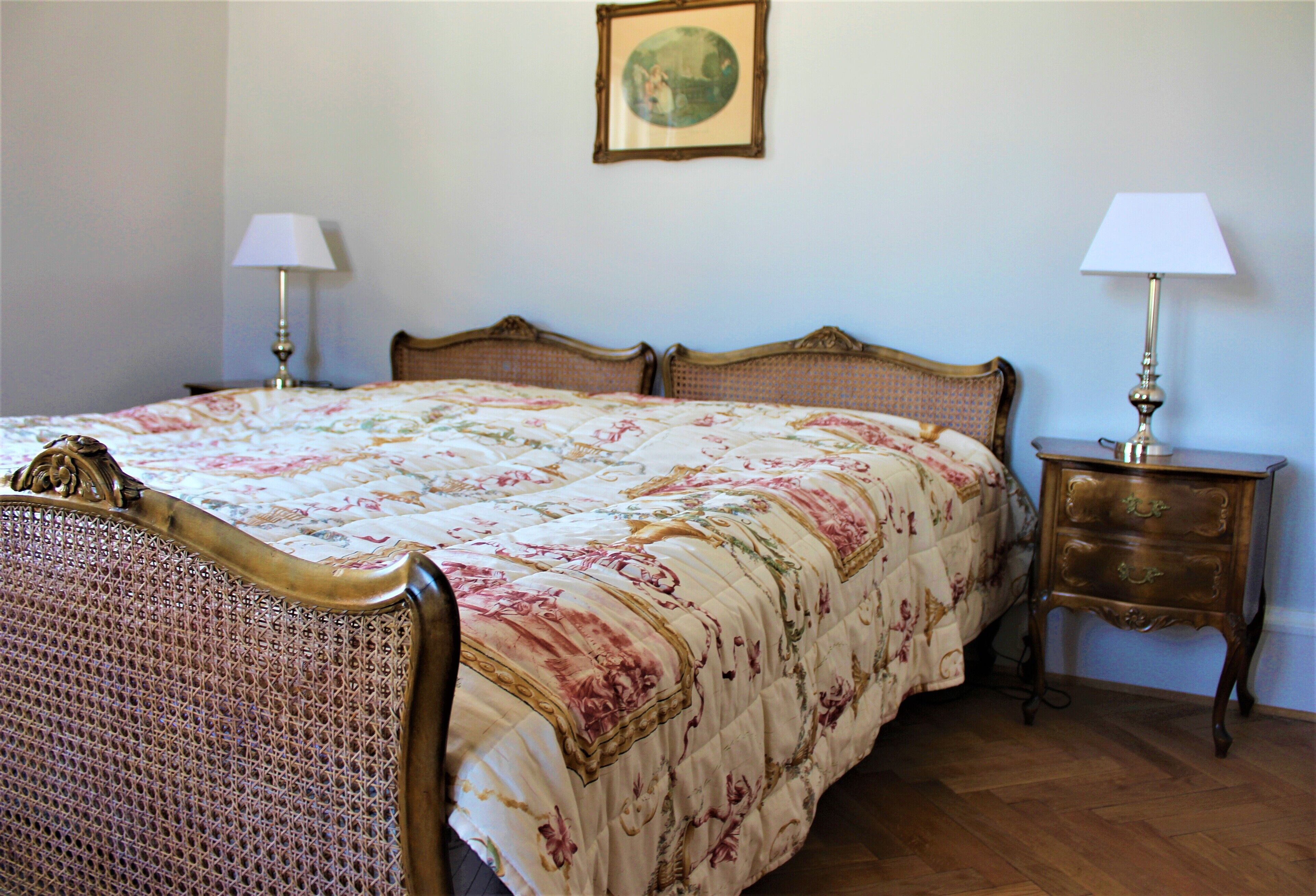 A bedroom with a four-poster bed, two bedside tables with lamps, and a framed picture on the wall.