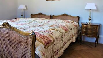 A bedroom with a four-poster bed, two bedside tables with lamps, and a framed picture on the wall.