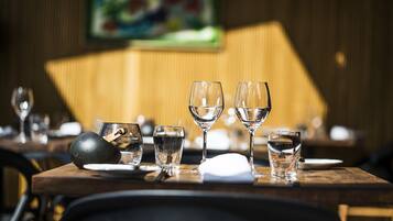 A dining table with various glassware and plates, set in a restaurant with a wooden interior and a painting on the wall.
