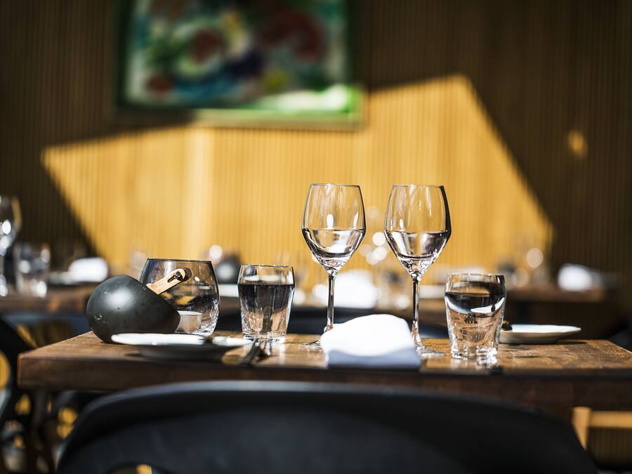 A dining table with various glassware and plates, set in a restaurant with a wooden interior and a painting on the wall.