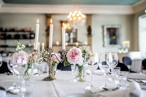 A dining table set with candles, glassware, and floral centerpieces.