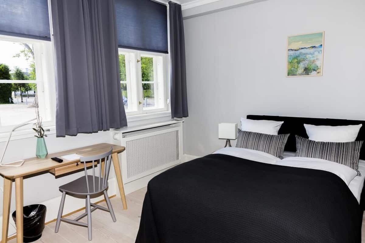 A bedroom with a bed, a desk, a chair, and a radiator.