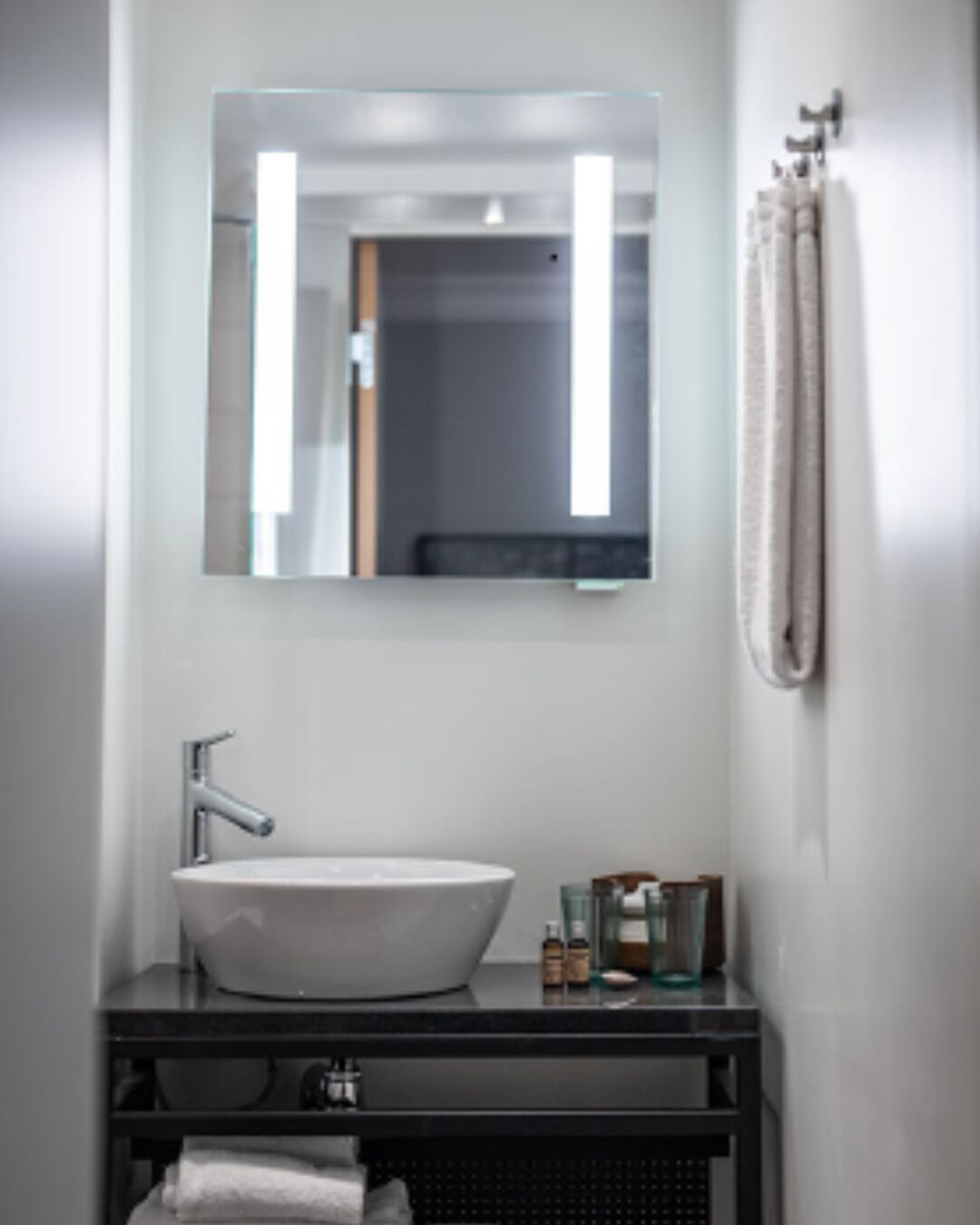 A bathroom with a white sink, a mirror, and a towel rack.