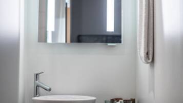 A bathroom with a white sink, a mirror, and a towel rack.