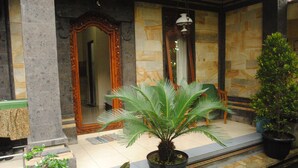 A well-maintained indoor garden with potted plants and a stone-tiled floor. - Jangkrik Homestay (Ubud)