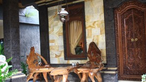 A wooden bench with a unique design, a large mirror, and a wooden cabinet. - Jangkrik Homestay (Ubud)