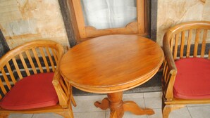 A wooden table with two chairs, each with a red cushion. - Jangkrik Homestay (Ubud)