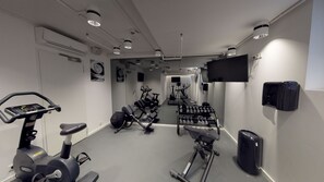 A modern gym with cardio equipment, weight benches, and dumbbells. - VISIONAPARTMENTS Berlin Otto-Braun-Strasse (Berlin)