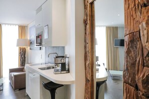 A modern kitchen with a built-in oven, a coffee machine, and a sink. There is a dining area with a table and chairs. - VISIONAPARTMENTS Berlin Otto-Braun-Strasse (Berlin)