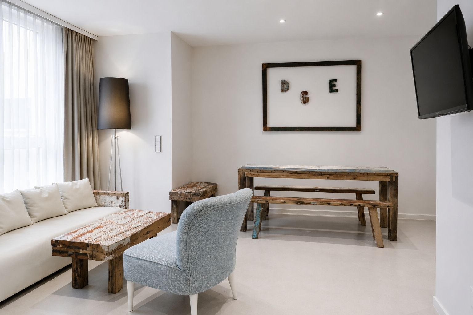 A modern living room with a sofa, a wooden coffee table, a blue armchair, a wooden bench, and a framed artwork on the wall.