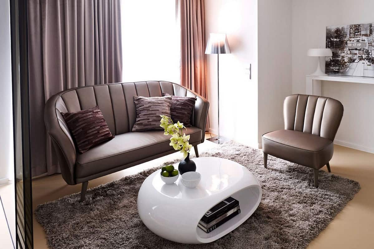 A modern living room with a leather sofa, a white coffee table, and a brown armchair.
