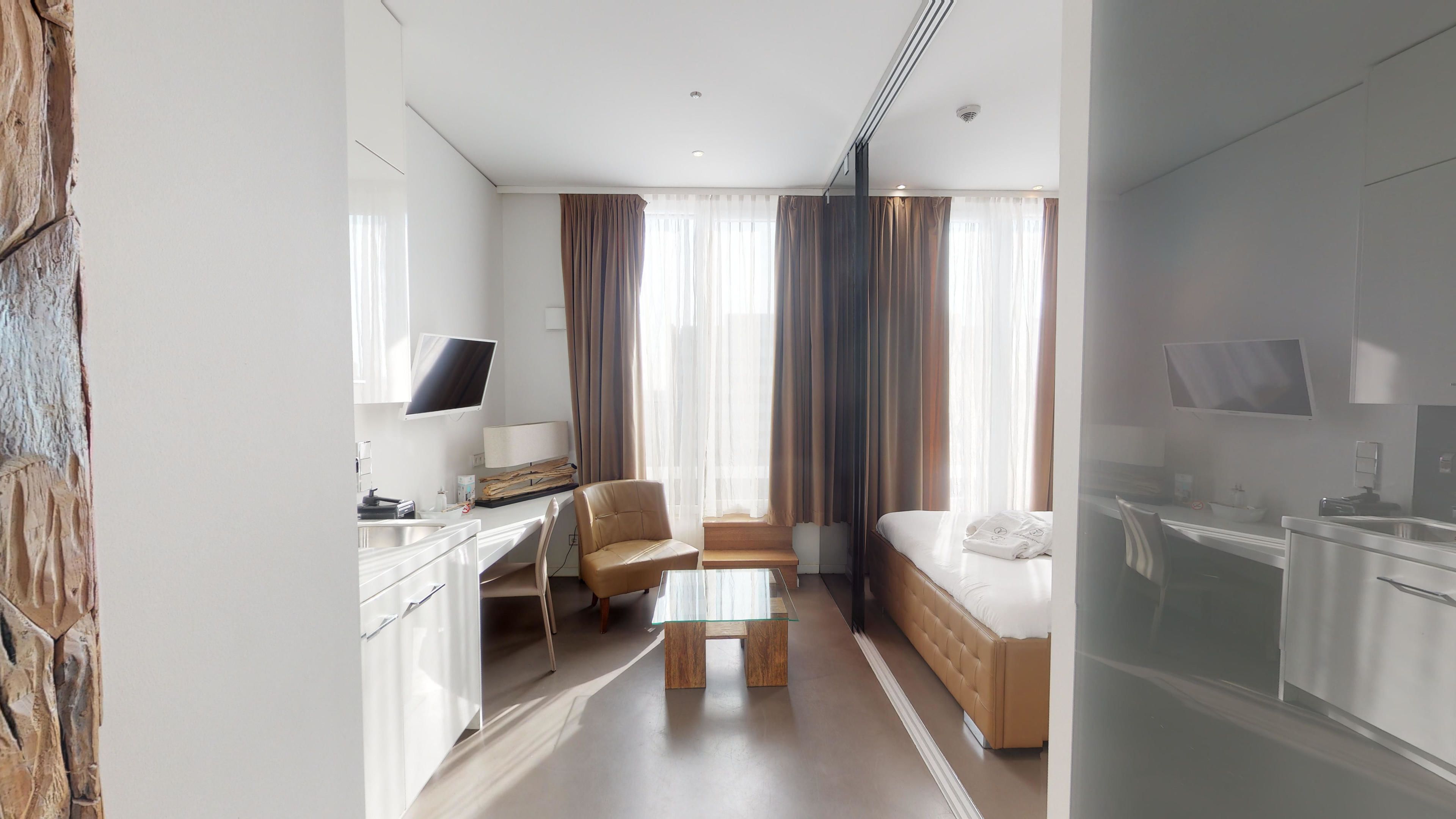 A hotel room with a desk, chair, sofa, and bed.