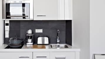 A modern kitchen with a microwave, toaster, kettle, and a sink.