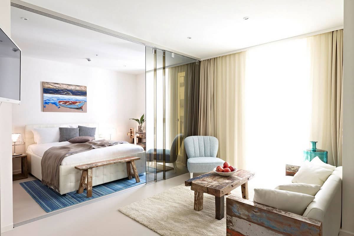A modern hotel room with a bed, a chair, a small table, and a sofa.