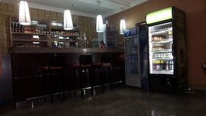 A bar area with a counter, stools, and a refrigerator stocked with beverages. - Ellis Suites Limited (Lagos)