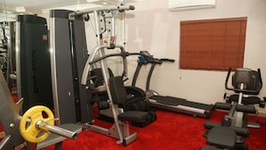 A gym with various exercise equipment, including a weight bench, a treadmill, and a squat rack. - Ellis Suites Limited (Lagos)
