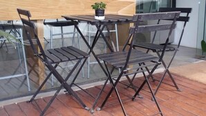 A small outdoor seating area with a wooden table and four metal chairs. - I Room Hotel (Surat Thani)