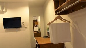 A bathroom with a wooden cabinet, a towel hanging on a rack, a television mounted on the wall, and a mirror. - I Room Hotel (Surat Thani)