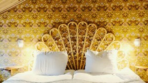 Un lit doté d’une tête de lit décorative, d’un papier peint à motifs floraux et de deux lampes de chevet.