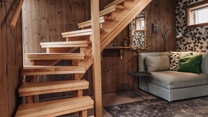 Un escalier en bois, un canapé et une petite table se trouvent dans une pièce aux murs en bois et au papier peint à motifs floraux.