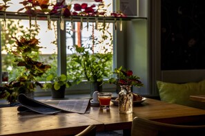A wooden table with a newspaper, a glass of orange juice, a vase with flowers, and a plate with a croissant. - Hotell Park (Vastervik)
