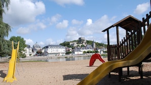 A sandy beach with a playground featuring a yellow slide and a red climbing structure.