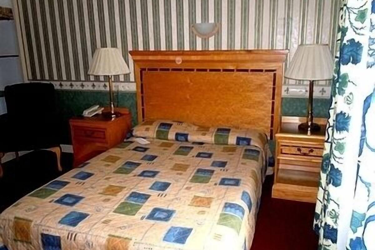 A hotel room with a bed, two bedside tables, a chair, and a striped wall.