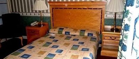 A hotel room with a bed, two bedside tables, a chair, and a striped wall.
