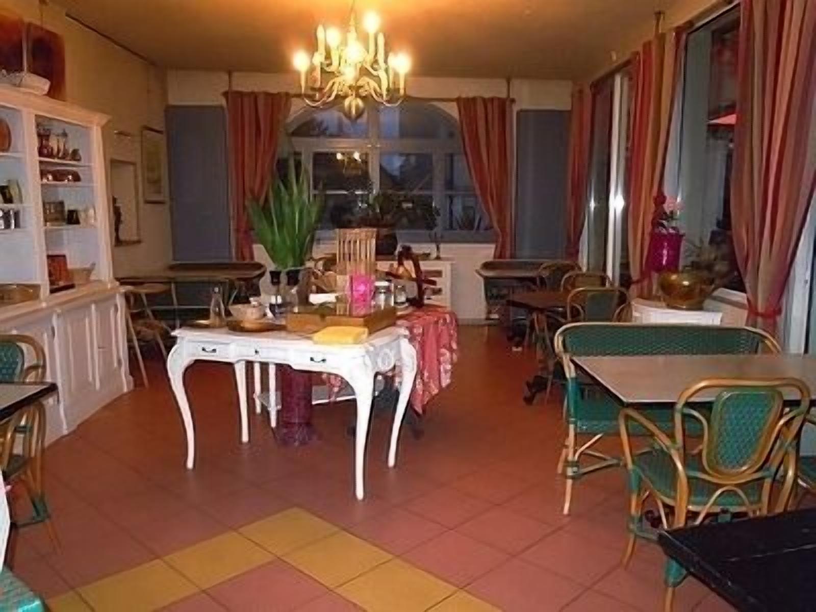A dining area with a chandelier, a table with a pink tablecloth, and chairs.