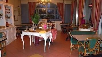 A dining area with a chandelier, a table with a pink tablecloth, and chairs.