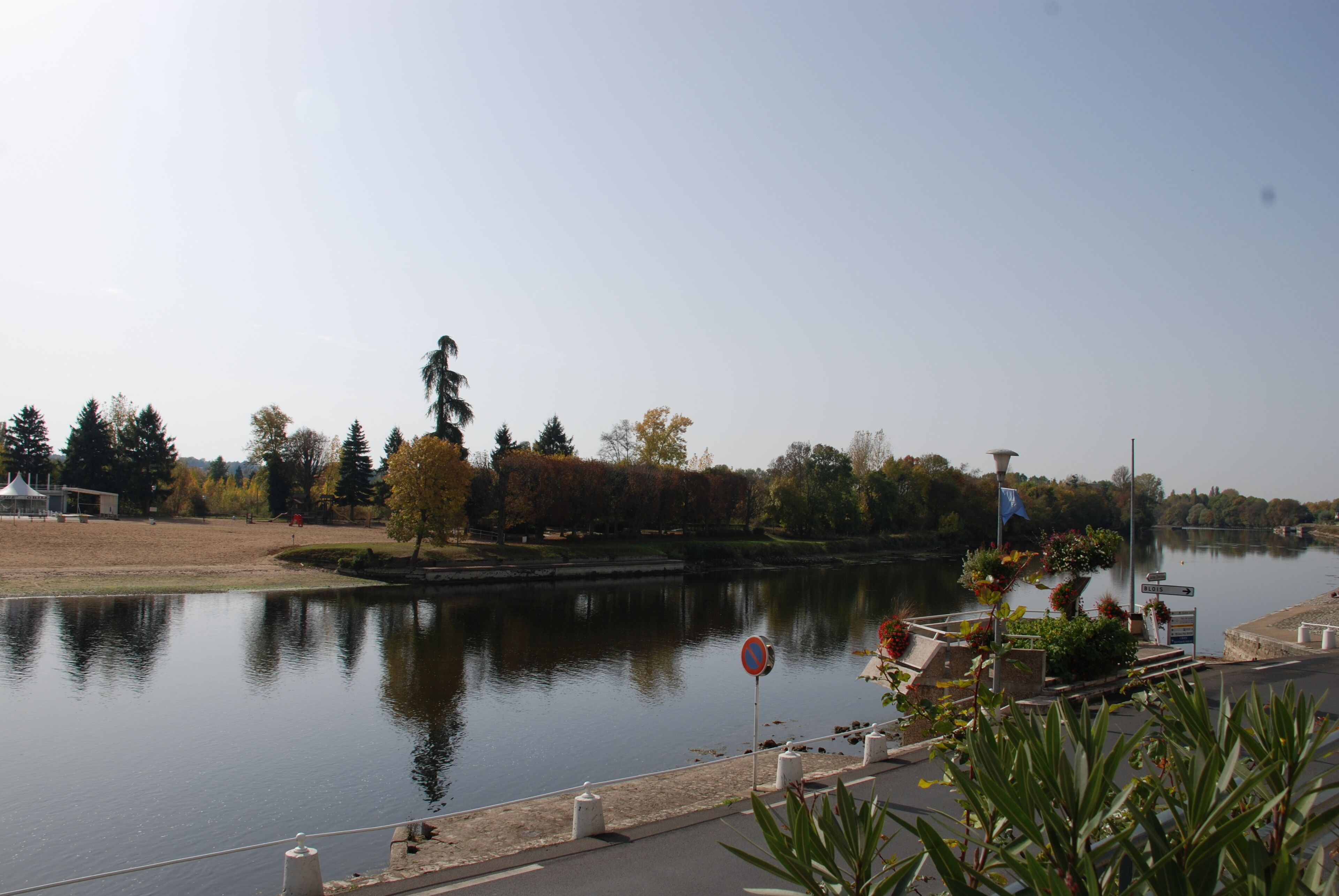 A calm river with a statue and trees in the background.