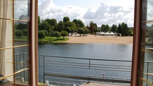 A view from a balcony overlooking a lake, with trees and a sandy area in the background.