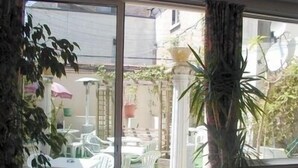 A room with a large window overlooking a patio area with outdoor furniture and plants.