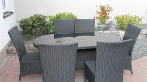A round table with four chairs, surrounded by greenery and a white wall. - Amalie B&B Apartments (Odense)