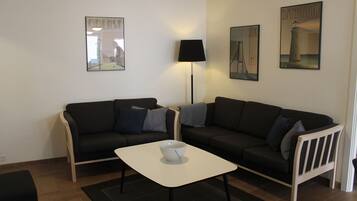 A living room with two black sofas, a white coffee table, and a floor lamp.