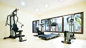A gym with cardio machines, weight training equipment, and large windows offering views of the outdoors.