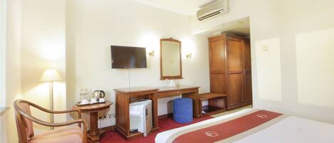 Ein Hotelzimmer mit Bett, Schreibtisch, Stuhl, Fernseher, Spiegel und Kleiderschrank.