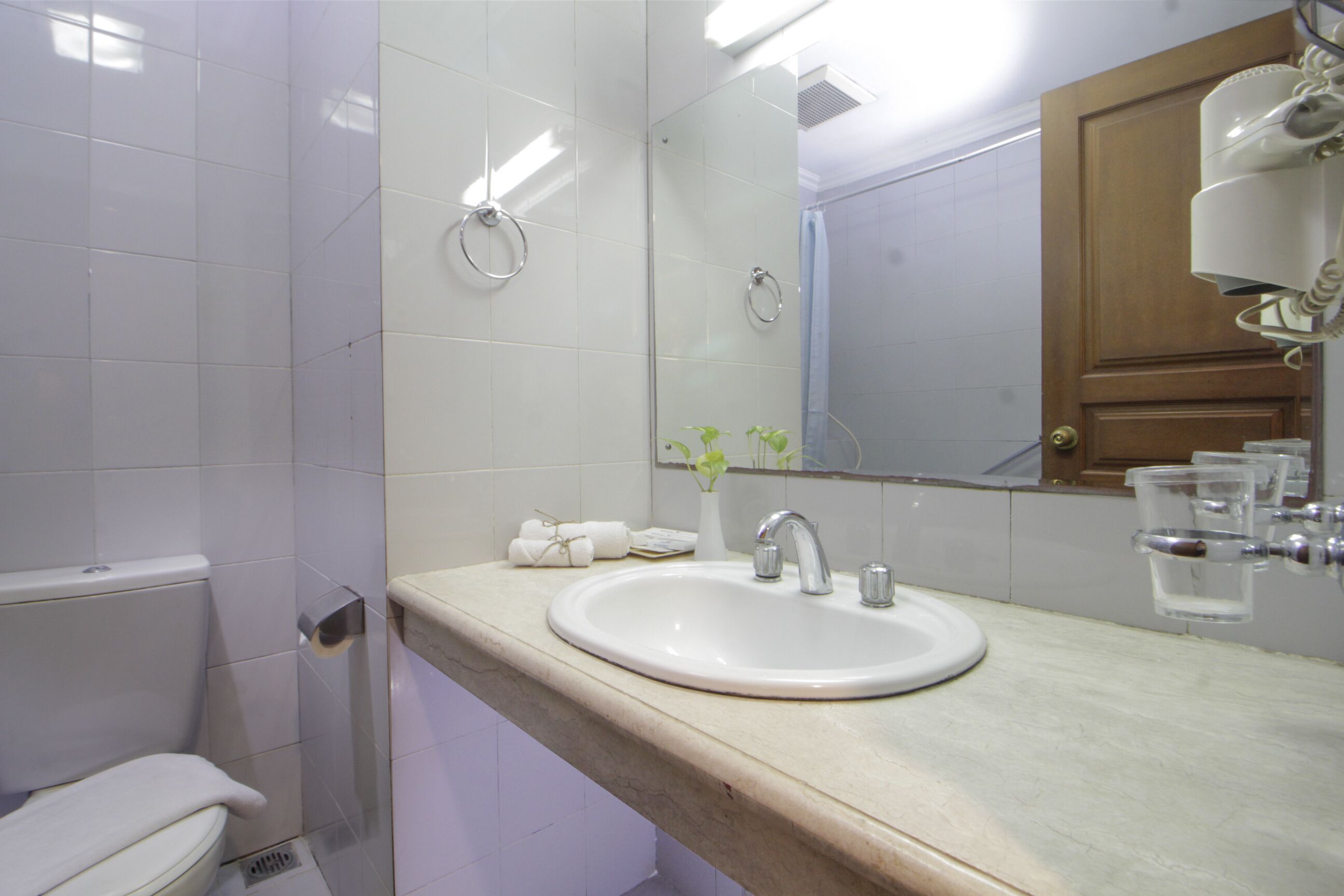 Une salle de bain avec un lavabo blanc, un miroir et une douche.