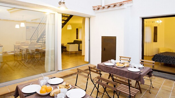 A dining area with tables set for breakfast, including plates, glasses, and orange slices. - Casa Babel Monfragüe (Torrejon El Rubio)