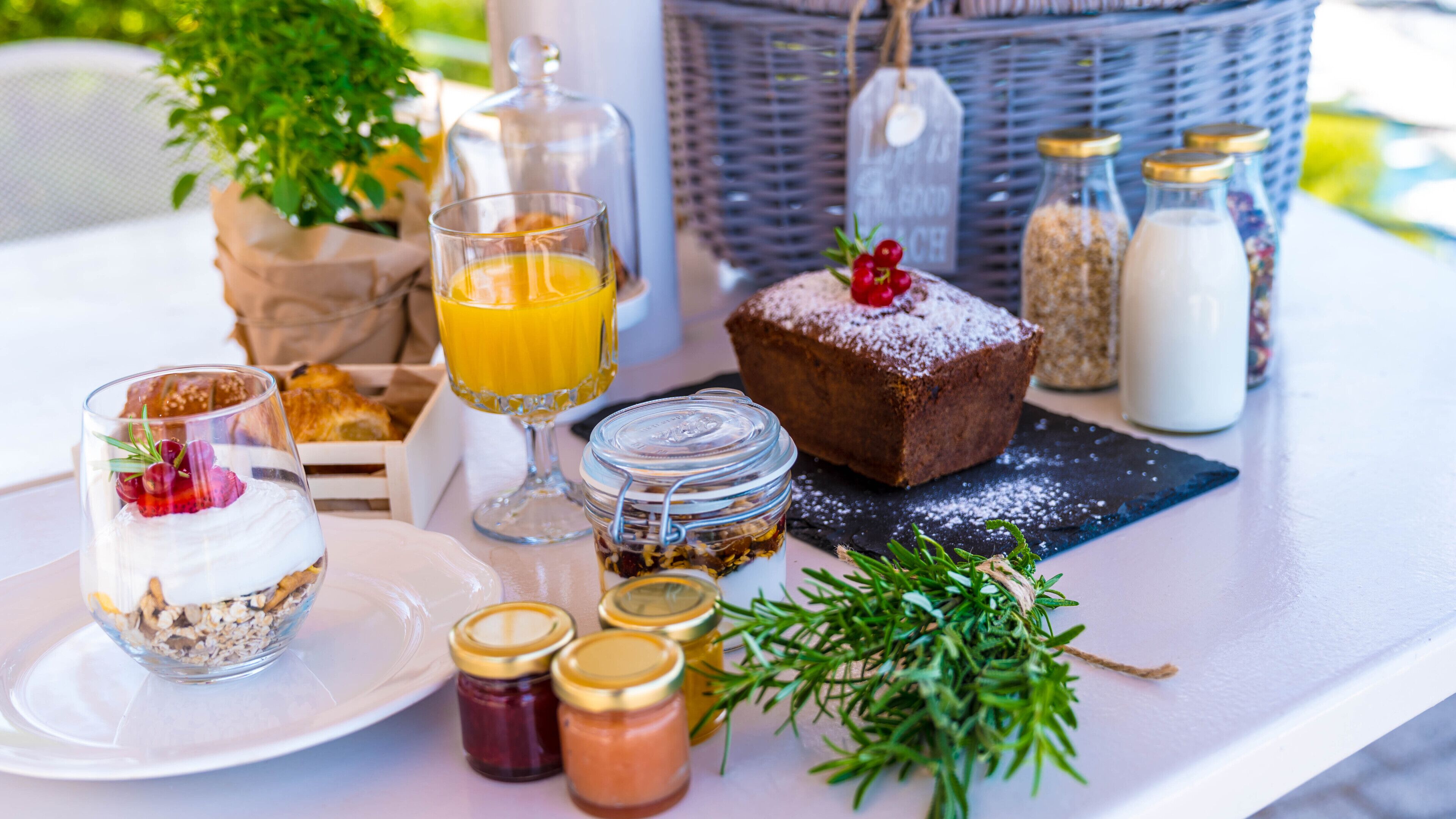 Un desayuno con diversos alimentos, como un muffin, un vaso de zumo de naranja y un tarro de mermelada.