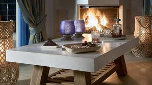 Un interior moderno con chimenea, una mesa dispuesta con bombones y nueces, y cristalería decorativa.