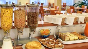 Ein Frühstücksbuffet mit Müsli, Granola und einer Obstschale.