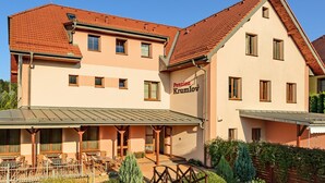 Ein zweistöckiges Gebäude mit rotem Ziegeldach, einer überdachten Außenlounge und einem gepflegten Rasen.