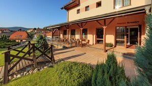 Ein Hotel mit überdachter Außenbereicherung, einer Holzbrücke und Blick auf die umliegende Landschaft.