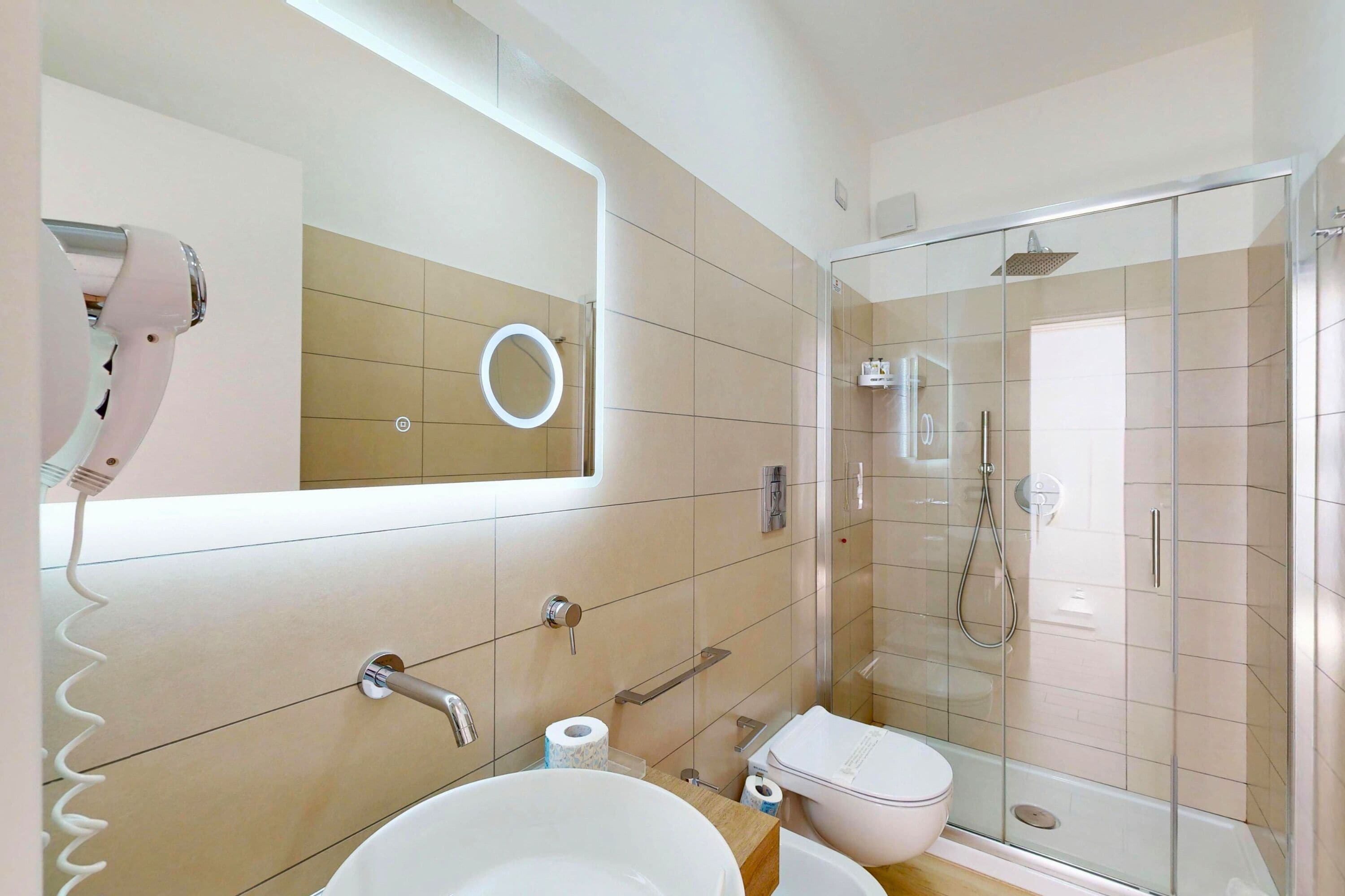 A bathroom with a sink, toilet, and a glass-enclosed shower area.