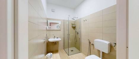 A modern bathroom with a toilet, sink, and glass shower enclosure.