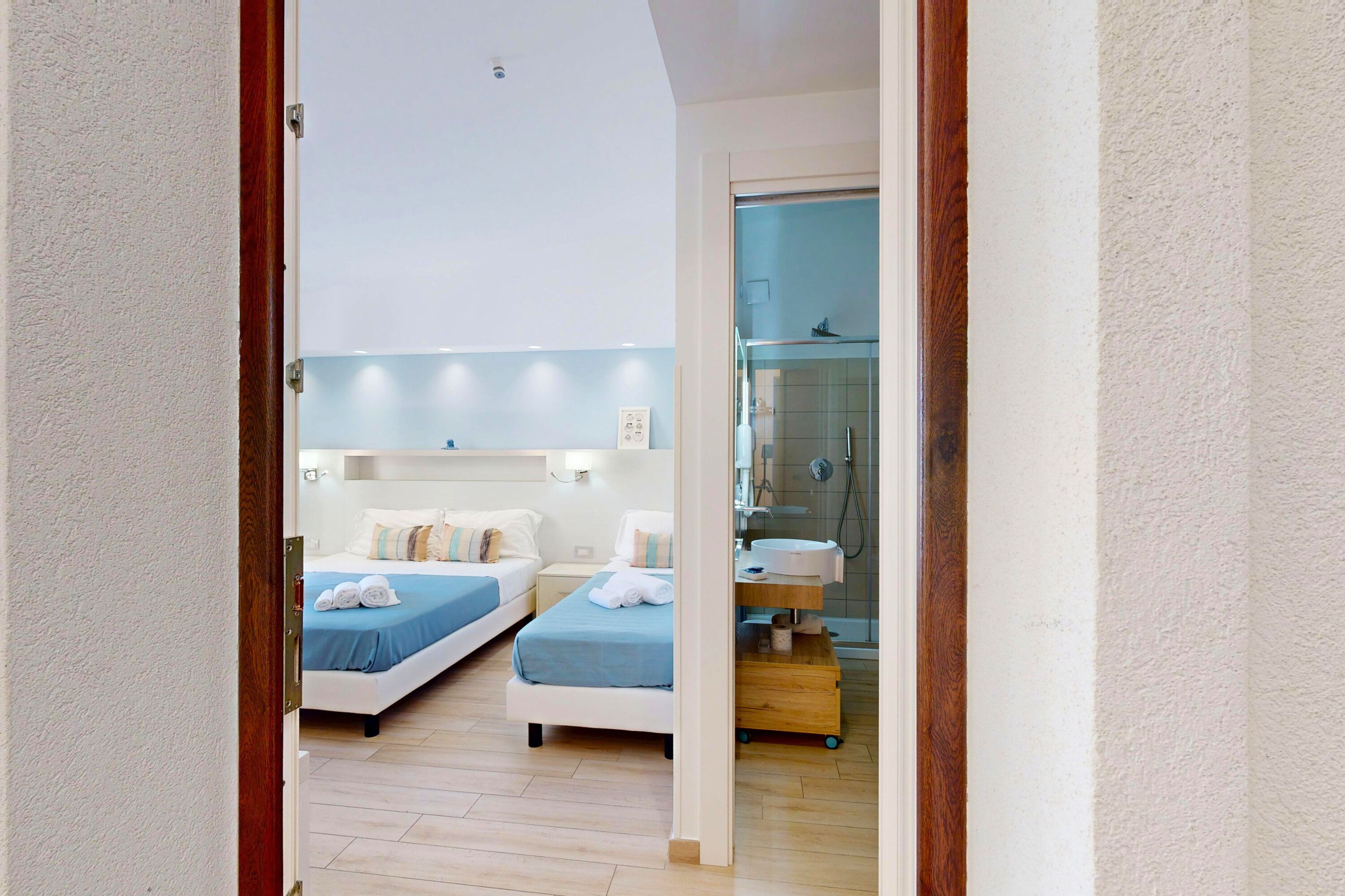 A hotel room with two beds, a shower, and a small bathroom.
