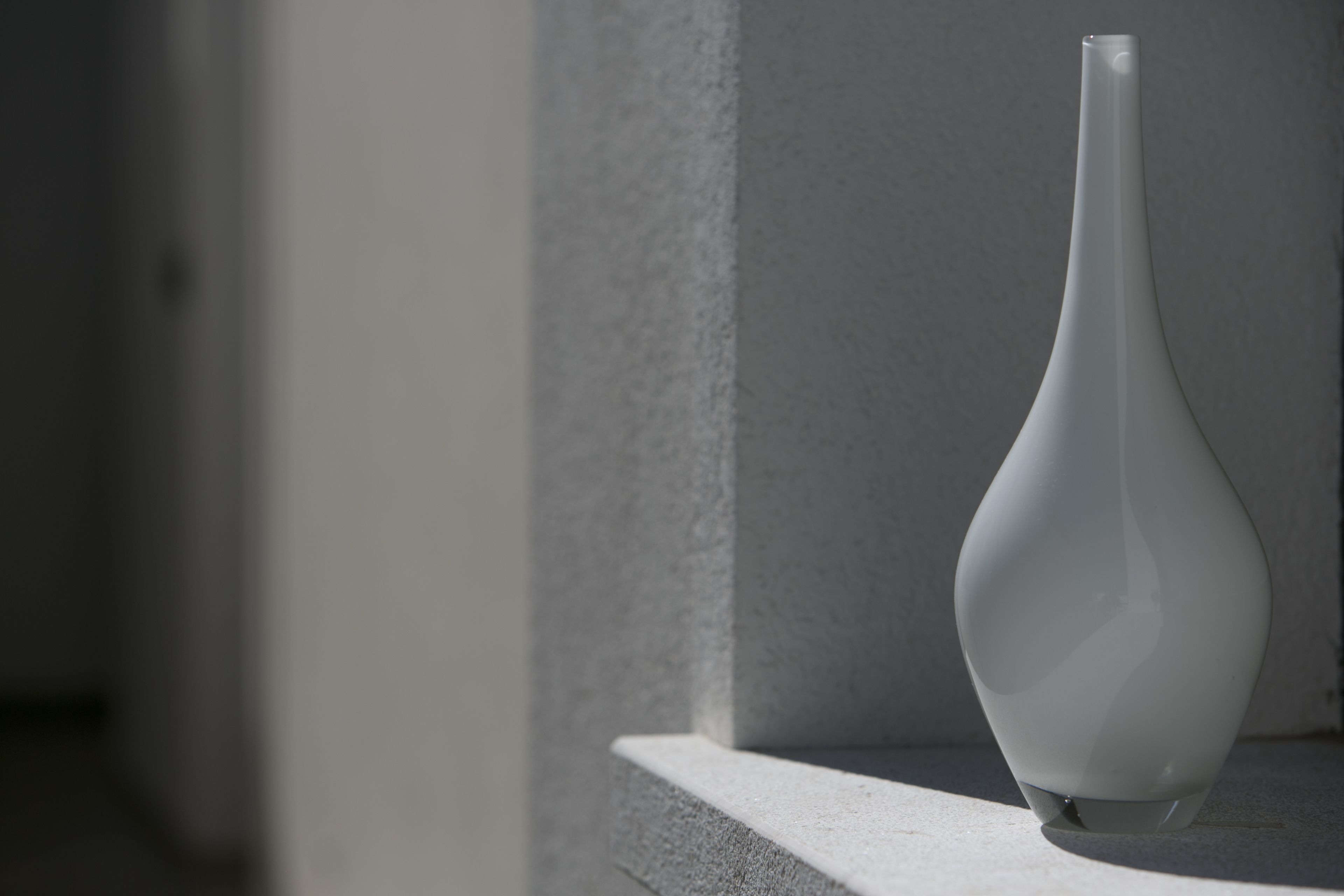 A white vase on a ledge.